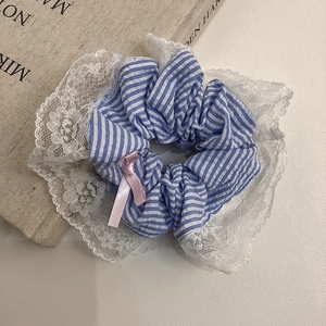 Détail d'un chouchou à rayures bleues avec dentelle brodée et petit nœud satiné rose