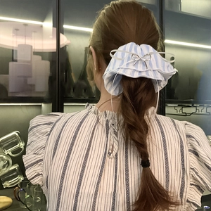 Blue and white striped scrunchie with a silver metal bow worn on a ponytail