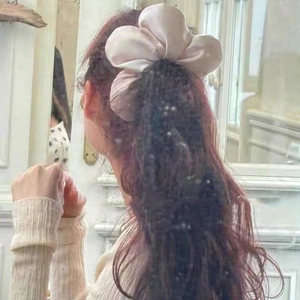 Elegante elastico in seta color champagne a forma di fiore, mostrato su una modella