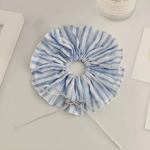 Detail of blue striped scrunchie with lace edge, silver bow charm and white ribbons