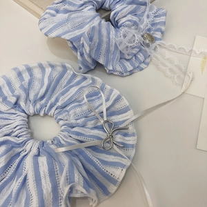 Detailed view of blue striped hair scrunchies with white lace edges and silver charms