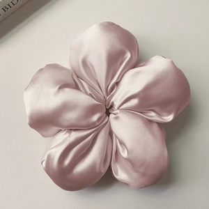 Dettaglio macro dell'elastico per capelli a fiore in raso rosa cipria lucido
