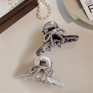 Detail of elegant acetate hair claw clip with silver bow and marble texture