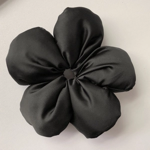 Dettaglio ravvicinato di un elastico per capelli a fiore 3D nero in morbido raso di lusso