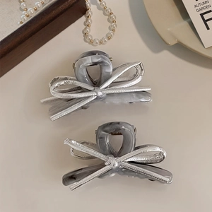 Close-up of marble acetate bow hair claw clips with silver metallic ribbon details