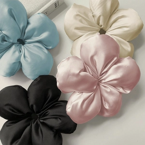 Dettaglio di quattro elastici per capelli a fiore in raso nei colori blu, bianco e rosa