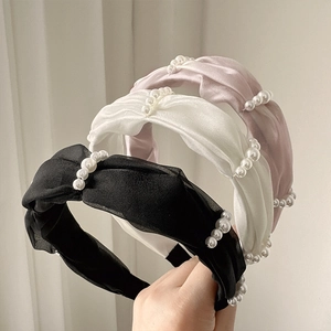 Detailed view of woven satin headbands with faux pearls in black, white, and pink tones