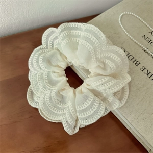 Vue macro détaillée du chouchou en dentelle crème avec broderie sur une surface en bois