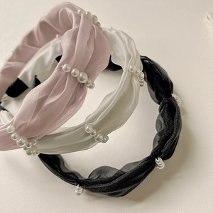 Close-up of twisted satin headbands with pearl beads in pink, beige and black