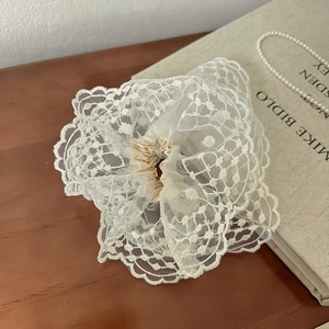 Détail d'un chouchou en dentelle crème sur un livre vintage avec collier de perles