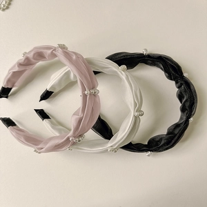 Detailed view of woven fabric headbands with elegant pearl accents in three classic colors
