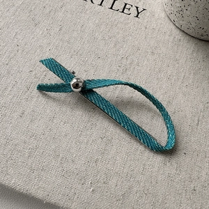 Pince à cheveux avec nœud en jean bleu et perle argentée sur fond en tissu gris