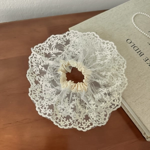 Détail de chouchou en dentelle blanc cassé avec texture en maille sur fond en bois
