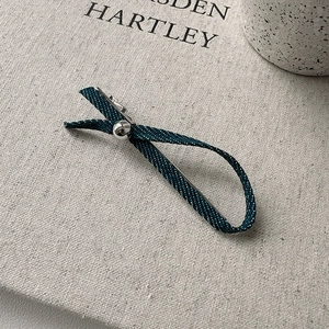 Détail de la pince à cheveux en denim à pois blancs avec perle métallique sur toile