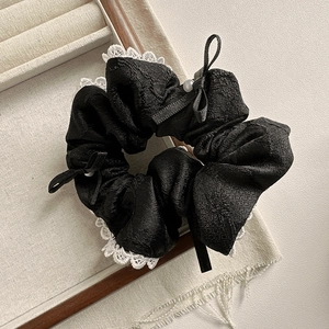Chouchou élégant en dentelle noire avec perle blanche et nœud sur plateau neutre