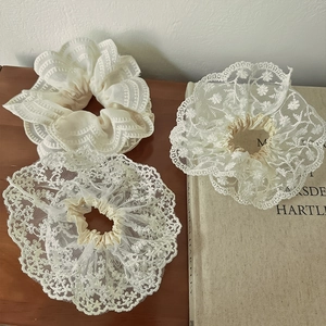 Lot de chouchous en dentelle blanc crème avec broderie florale sur un bureau vintage