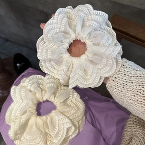Gros plan sur un chouchou en dentelle blanc crème avec broderie florale et texture fine