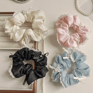 Détails de quatre chouchous en dentelle avec nœuds en satin et perles sur plateau en bois