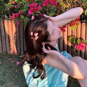 Détail de petites pinces à cheveux à nœuds roses sur de longs cheveux bruns ondulés