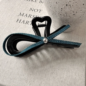 Détail de la pince à cheveux nœud en denim avec cœur ajouré et fini poli noir