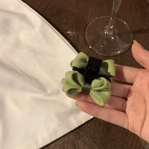 Détail d'une pince à cheveux à nœud en tissu vert avec texture tricotée en main