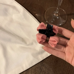 Vue détaillée d'une petite pince à cheveux avec nœud en tissu rose sur fond de bois