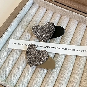 Detailed macro view of heart-shaped rhinestone hair clips on a soft velvet jewelry box