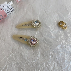 Close-up of heart crystal hair clips and gold hoop earrings on white texture
