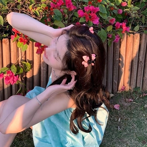 Lot de pinces à cheveux nśud rose portées sur cheveux ondulés dans un jardin ensoleillé