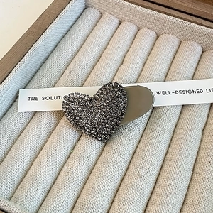 Macro shot of heart-shaped hair clip with dark grey crystals in a velvet jewelry box