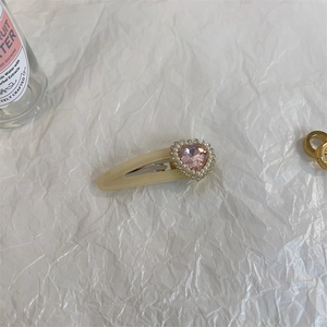 Close-up of heart-shaped pink gemstone hair clip with pearl trim on white background