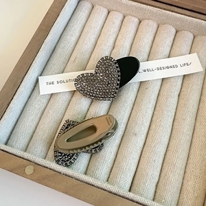 Detail of heart-shaped rhinestone hair clips set in a wooden jewelry display case