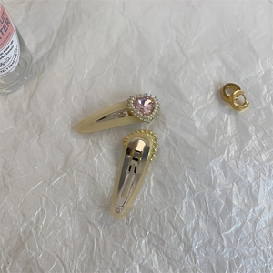 Detail of cream yellow hair clips with pink heart rhinestone and pearl accents