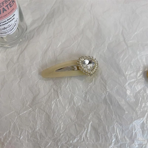 Sweet cream-colored heart hair clip with rhinestones and pearls on white background