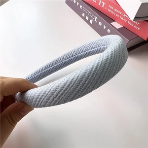 Close-up of light blue waffle knit headband with thick sponge padding on pastel background