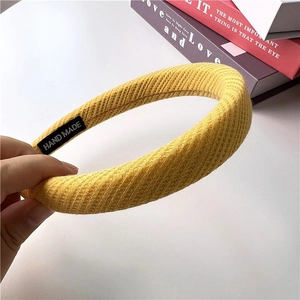 Detail of handmade ginger yellow waffle knit headband with woven texture and side label