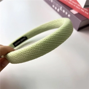 Macro shot of light green waffle fabric headband featuring the handmade woven label