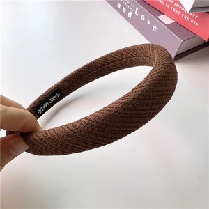 Close-up of brown knitted waffle headband with handmade label and thick ribbed texture