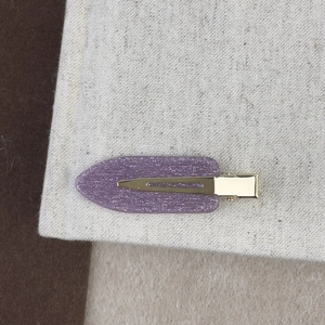 Vue détaillée d'une pince à cheveux violette pailletée sur fond en lin texturé