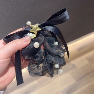 Detail des schwarzen Haargummis mit Perlen, Seidenschleife und goldenem Sternanhänger