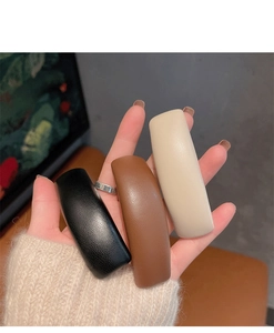 Close-up of three rectangle leather hair clips in black, brown and beige colors