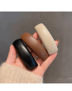 Detailed view of three faux leather hair clips in black brown and cream with lychee texture