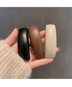 Close-up of three faux leather hair clips in black brown and beige with litchi texture