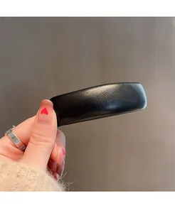 Close-up of minimalist black leather hair clip with fine lychee grain texture and rectangular design