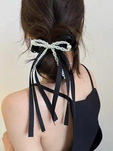 Detail of elegant black bow hair tie with white pearls on a high ponytail style