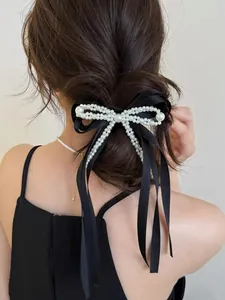 Detail of elegant black satin bow hair tie with embedded white pearls on high ponytail