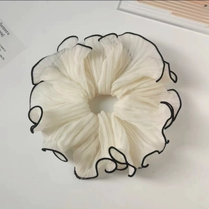 Detailed close-up of a large pleated chiffon scrunchie with elegant black scalloped edges