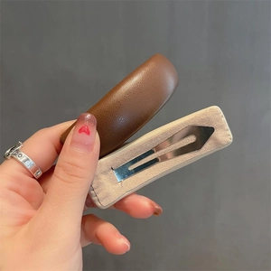 Minimalist beige and brown leather hair clip set for women held in hand