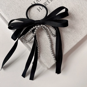 Detail of black ribbon hair tie featuring layered silver beaded chains and satin texture