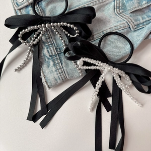 Elegant black bow hair scrunchies with faux pearls and silver beads on denim background